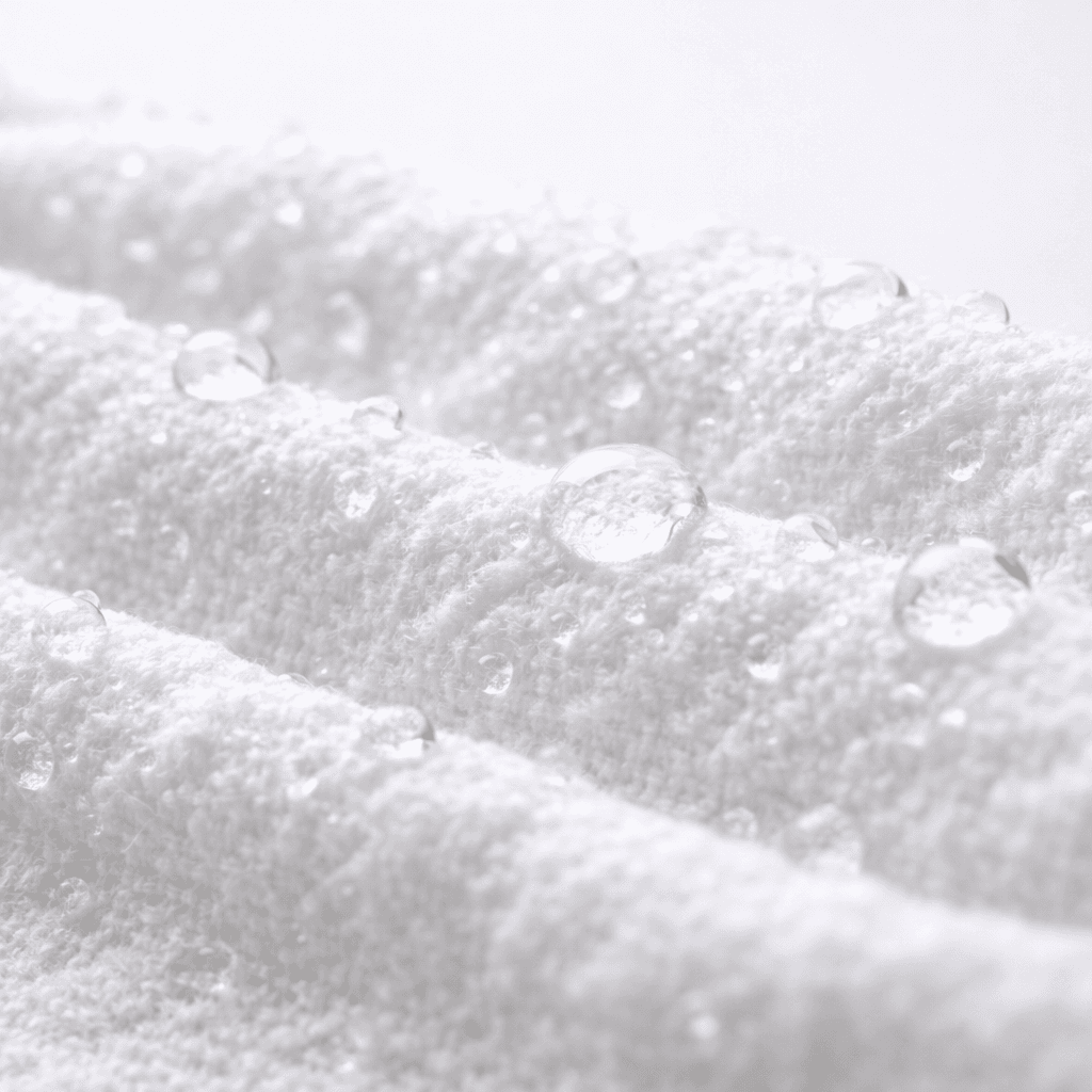Close-up of UNICORN wet wipe fabric texture showing thick, soft spunlace material with water droplets